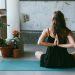 woman wearing black shirt sitting on green yoga mat