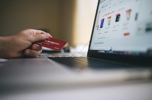 Person holding a credit card while shopping online on a laptop, indicating ecommerce transactions.